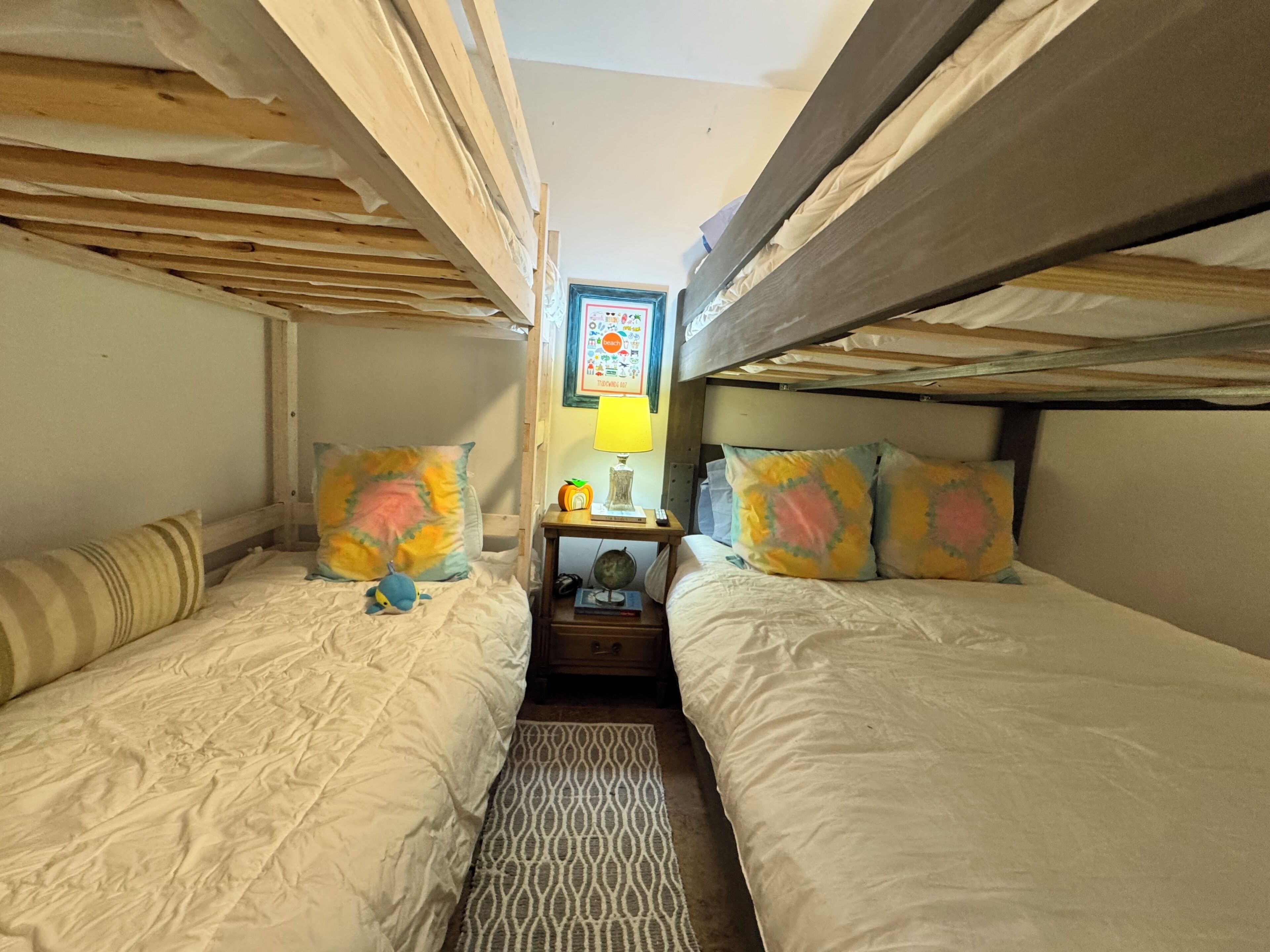 A bunk bed room with a small table and a lamp between the beds.