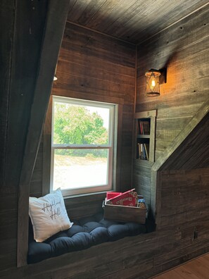 A cozy attic bedroom with a built-in window seat, a bookshelf, and a lantern. - Charming barn in Glasgow, modern amenities, private setting close to downtown (Glasgow)