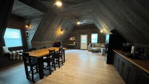 A spacious attic room with a wooden dining table, chairs, a sofa, and a kitchen area. - Charming barn in Glasgow, modern amenities, private setting close to downtown (Glasgow)