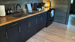 A modern kitchen with dark cabinetry, a wooden countertop, and a sloped ceiling. - Charming barn in Glasgow, modern amenities, private setting close to downtown (Glasgow)