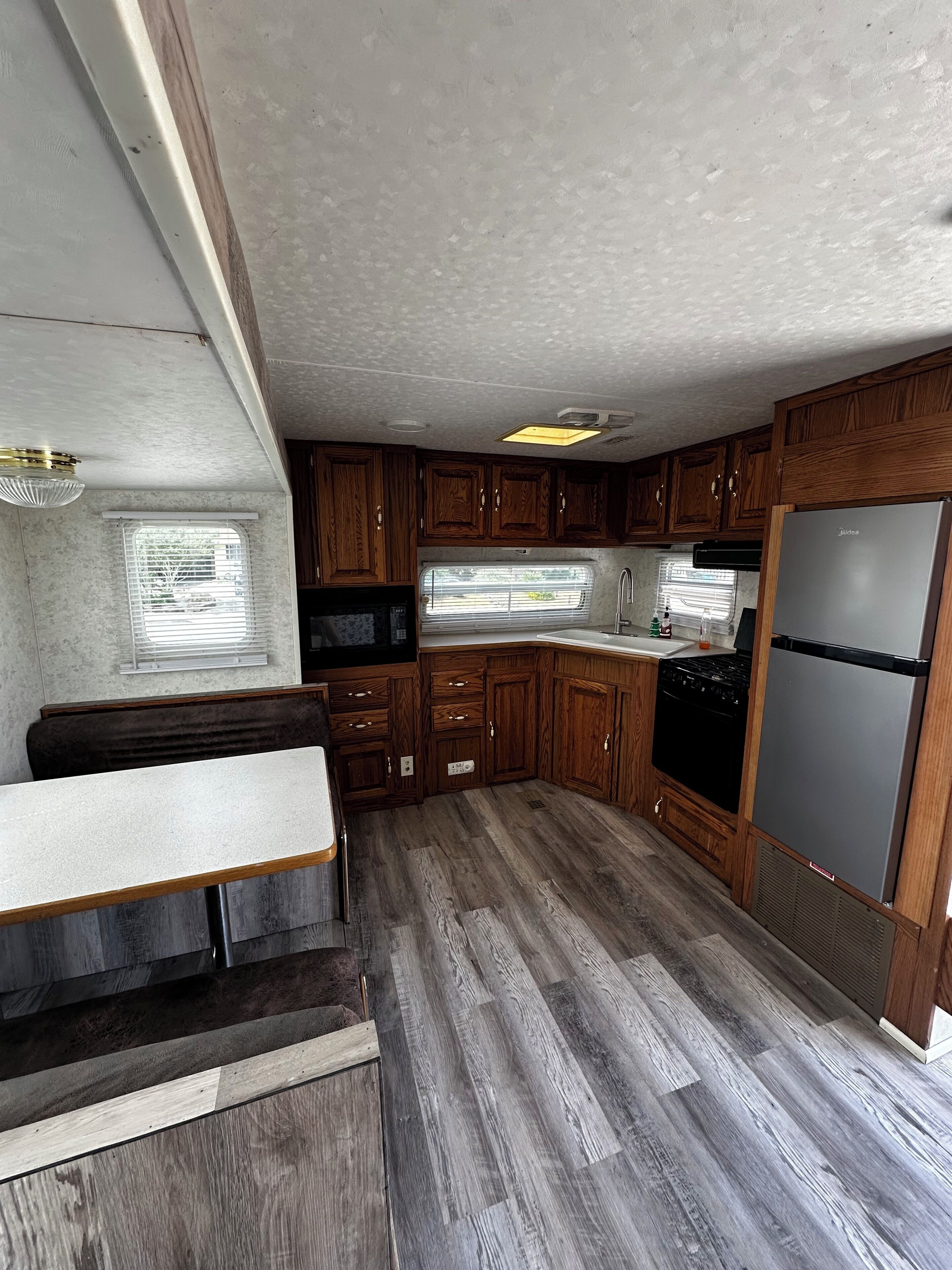 A compact RV kitchen with wooden cabinets, a built-in stove, and a refrigerator.