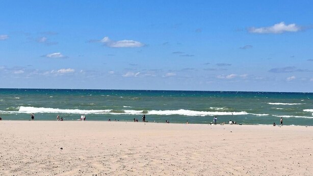 Ein Strand mit blauem Himmel und ruhiger See.