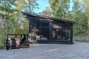 Een moderne cabin met grote ramen, een terras en een trap naar de ingang.