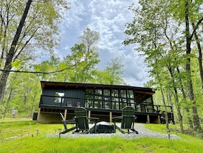 Eine Hütte mit einer Terrasse, zwei Stühlen und einem überdachten Grillbereich.