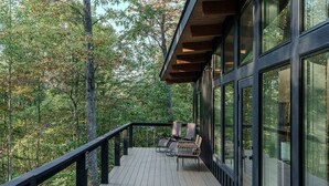 A wooden deck with a railing, overlooking a forested area. - The Briar House-A modern retreat in Hocking Hills (McArthur)