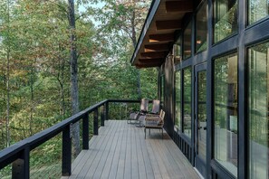 A wooden deck with a railing, overlooking a forested area. - The Briar House-A modern retreat in Hocking Hills (McArthur)