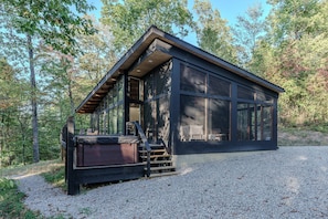 A modern cabin with large windows, a hot tub, and a gravel driveway. - The Briar House-A modern retreat in Hocking Hills (McArthur)