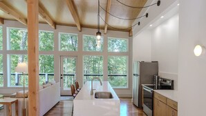 A modern kitchen with large windows, wooden beams, and a central island. - The Briar House-A modern retreat in Hocking Hills (McArthur)