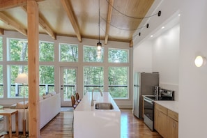 A modern kitchen with large windows, wooden beams, and a central island. - The Briar House-A modern retreat in Hocking Hills (McArthur)