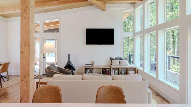 A modern living room with a large window, a fireplace, and a flat-screen TV. - The Briar House-A modern retreat in Hocking Hills (McArthur)