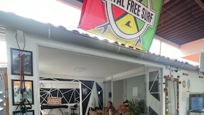 A restaurant with a sign reading "Natal Free Surf" and a dining area with a table and chairs. - Pousada e Hostel Natal Free Surf (Natal)