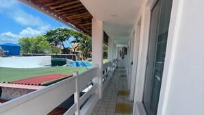 A covered corridor with a tiled floor, white railings, and a view of a sports field. - Pousada e Hostel Natal Free Surf (Natal)