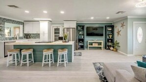 A modern kitchen with a central island, bar stools, and a dining area with a TV. - Entire home in Matlacha Isles-Matlacha, Florida
4 guests 2 bedrooms 3 beds (Matlacha Isles-Matlacha Shores)