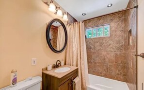 Bathroom features a large mirror above a sink, patterned tile walls, and a shower curtain with a geometric design.
