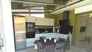 A modern kitchen with a dining table set for four, a refrigerator, and a stove. - Gîte Charles - CAPBRETON (CAPBRETON)