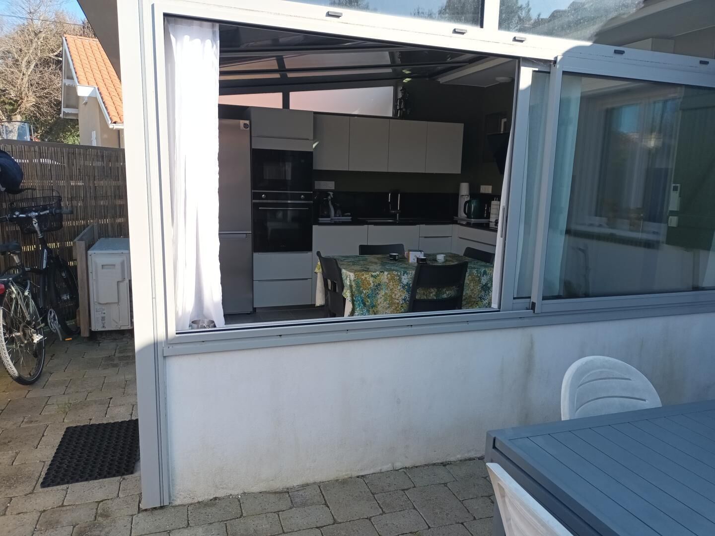 A compact kitchen with modern appliances, a dining area with a table and chairs, and a bicycle parked outside.
