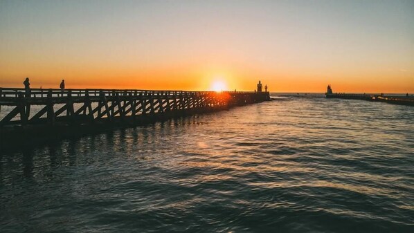 A pier extending into calm waters at sunset.