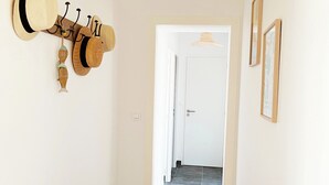 A hallway with a wall-mounted hat rack, a woven ceiling light fixture, and a tiled floor. - Close to the beach! Family home with a large patio/garden—sleeps 9 (Longeville-sur-Mer)
