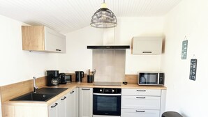 A compact kitchen with a black sink, white cabinets, a microwave, and a coffee maker. - Close to the beach! Family home with a large patio/garden—sleeps 9 (Longeville-sur-Mer)