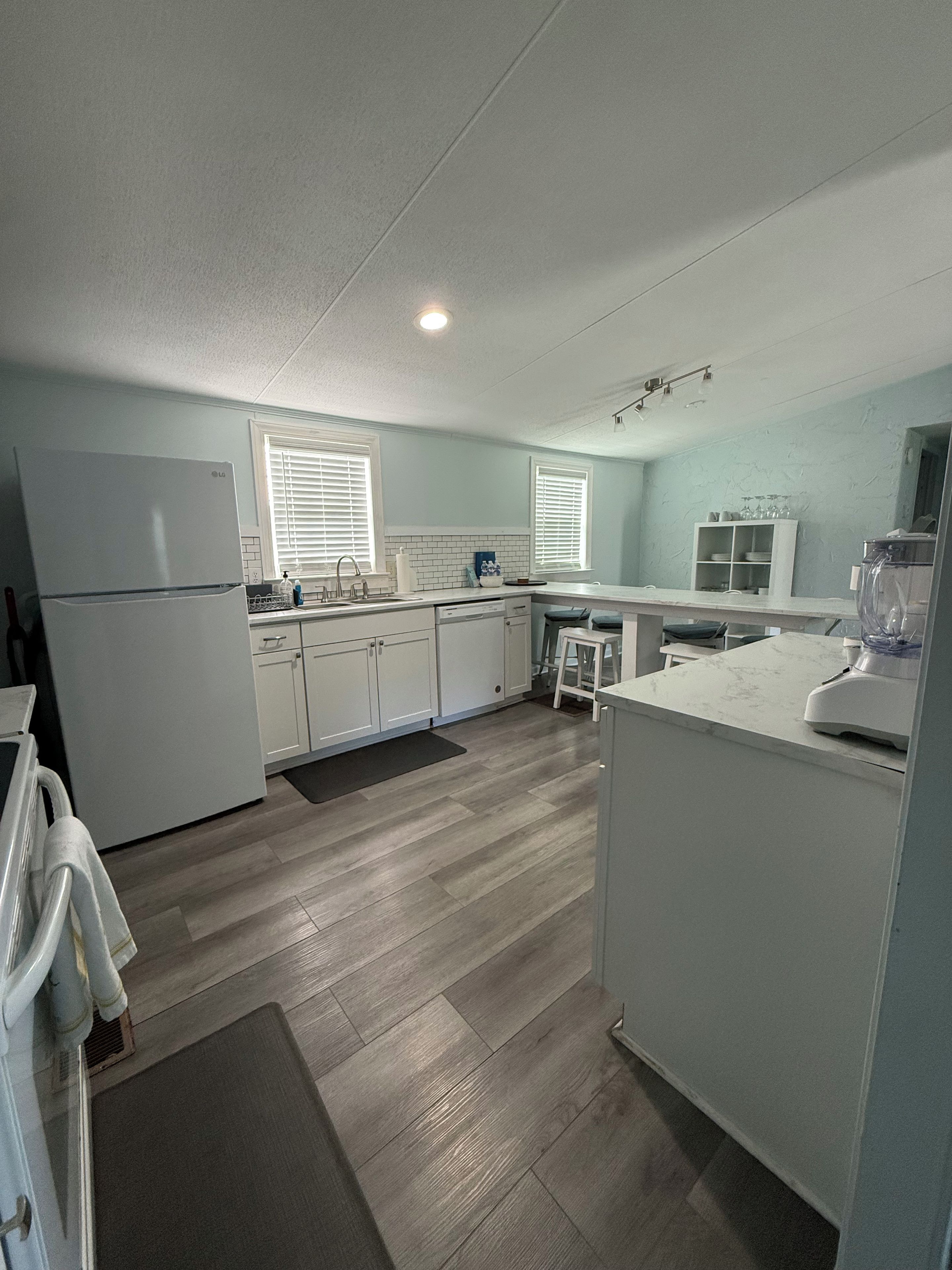 A modern kitchen with white cabinetry, a built-in dishwasher, and a refrigerator.