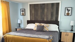 Une chambre à coucher avec un lit, des tables de chevet, une tête de lit en bois et un luminaire au plafond.