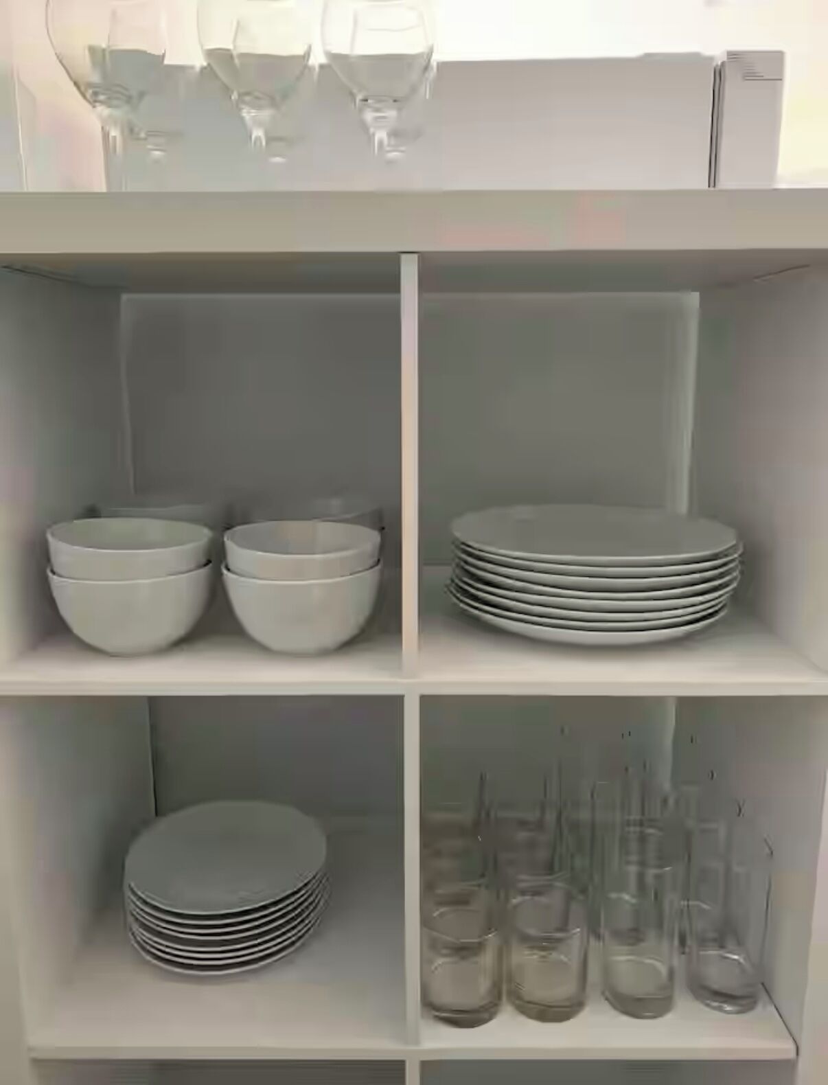 Une étagère blanche contenant des bols, des assiettes et des verres.