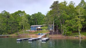 Ein Haus mit einem Steg, der in einen See führt, umgeben von dichtem Baumbestand.