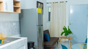 A compact kitchen with a refrigerator, a coffee maker, and a dining area with a table and chairs. - Casa Oriente (San Miguel)