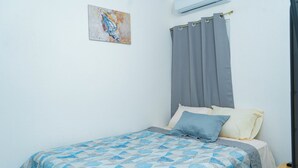 A bedroom with a bed, a painting on the wall, and an air conditioning unit. - Casa Oriente (San Miguel)