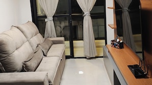 A modern living room with a sofa, a wooden TV stand, and a ceiling light. - Summer dream. Beach House: The Perfect Place to Relax and Enjoy! (Recreio dos Bandeirantes Rio de Janeiro)