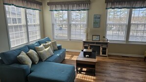 A living room with a blue sofa, patterned cushions, a wooden coffee table, and a fireplace. - 4bedroom Beach Retreat in charming Long Neck with Rooftop View and lounging deck (Long Neck)