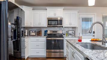 A modern kitchen with white cabinets, stainless steel appliances, and a granite countertop.