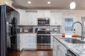 A modern kitchen with white cabinets, stainless steel appliances, and a granite countertop.