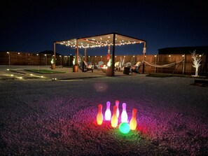 An outdoor area with a covered seating area and a bowling alley setup.