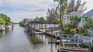 A waterfront property with docked boats, a covered pier, and a house with a balcony overlooking the water.