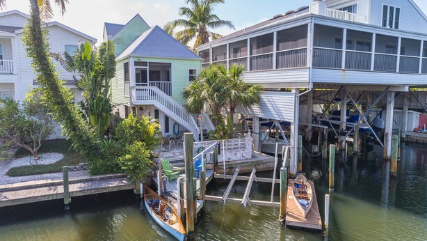 A waterfront property with a dock, a small boat, and a house with a balcony.