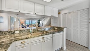 A modern kitchen with white cabinetry, granite countertops, and a built-in dishwasher.