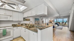 A spacious kitchen with white cabinetry, a granite countertop, and a large island.