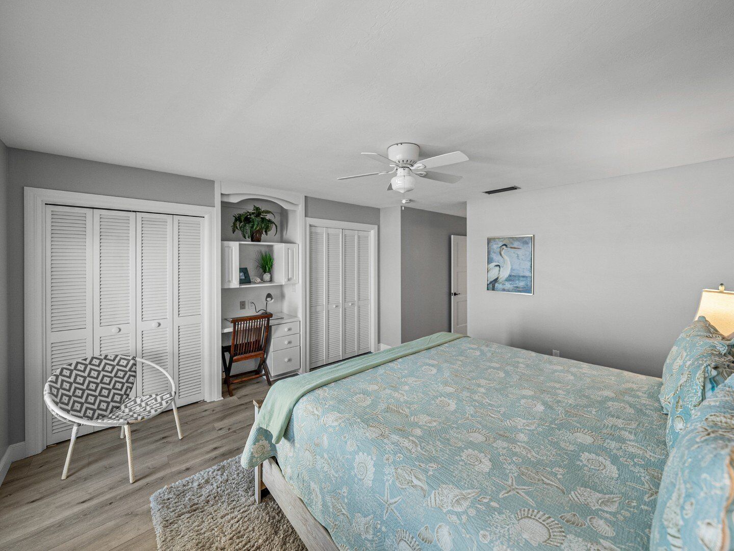 A bedroom with a bed, a chair, a desk, and a ceiling fan.