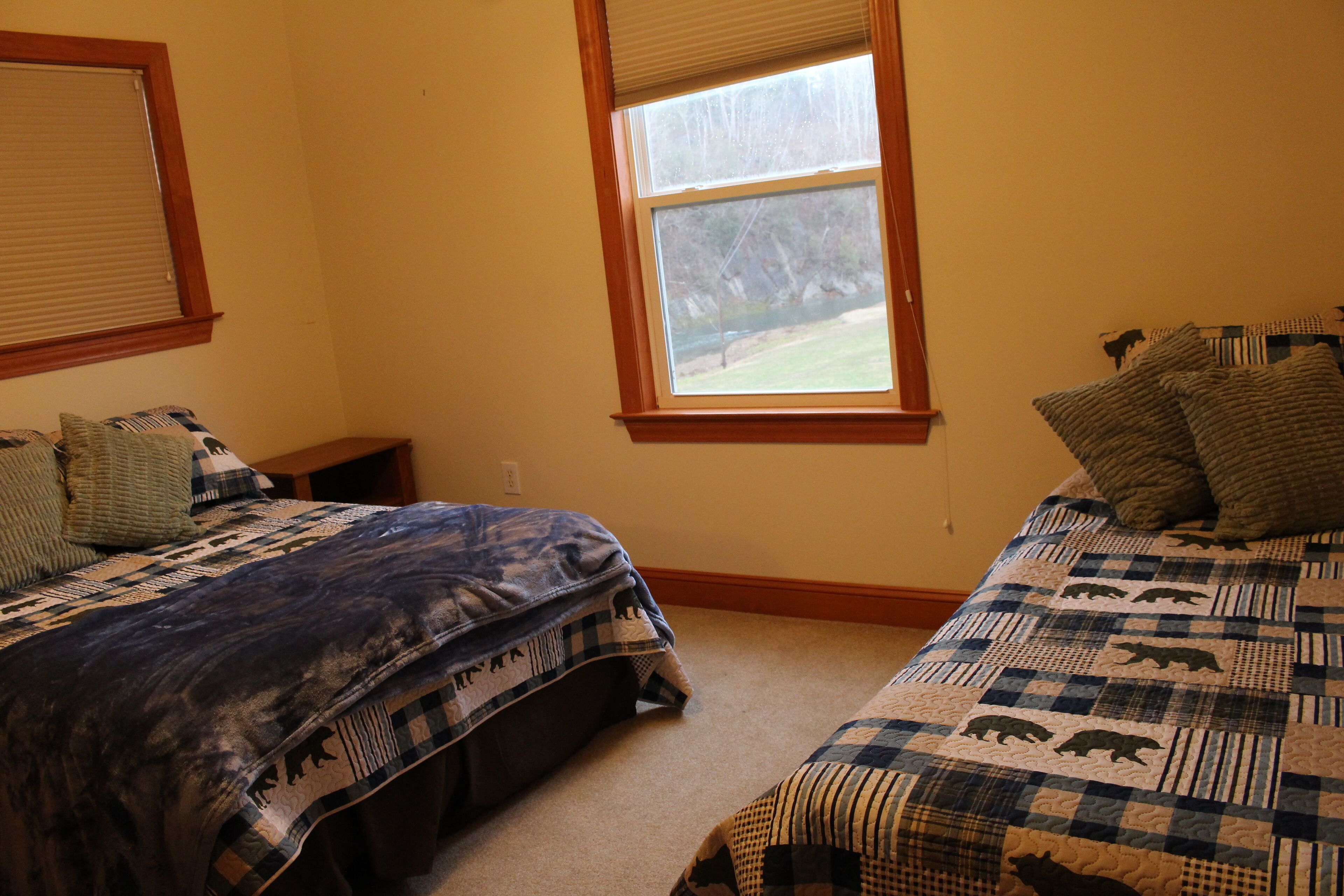 A bedroom with two beds, each with a patterned quilt and pillows.