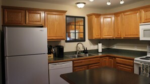Una cocina con armarios de madera, un refrigerador, un lavavajillas, un fregadero y una estufa.