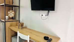 A small, modern room with a desk, chair, and a mounted TV. - Luizas Apartments  (Sarandë)