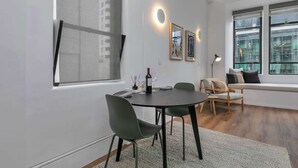 Ein modernes Wohnzimmer mit einem runden Esstisch, zwei Stühlen, einer Couch und einem großen Fenster mit Blick.