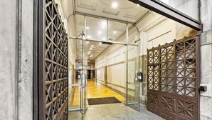 Ein Hotel Eingang mit Glastür, einem Metallgitter und einem gefliesten Boden.