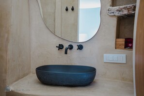 A bathroom with a round mirror, a black basin, and a wall-mounted light switch. - Zen Blue Suites Luxury and Nature in Kea (Kea)