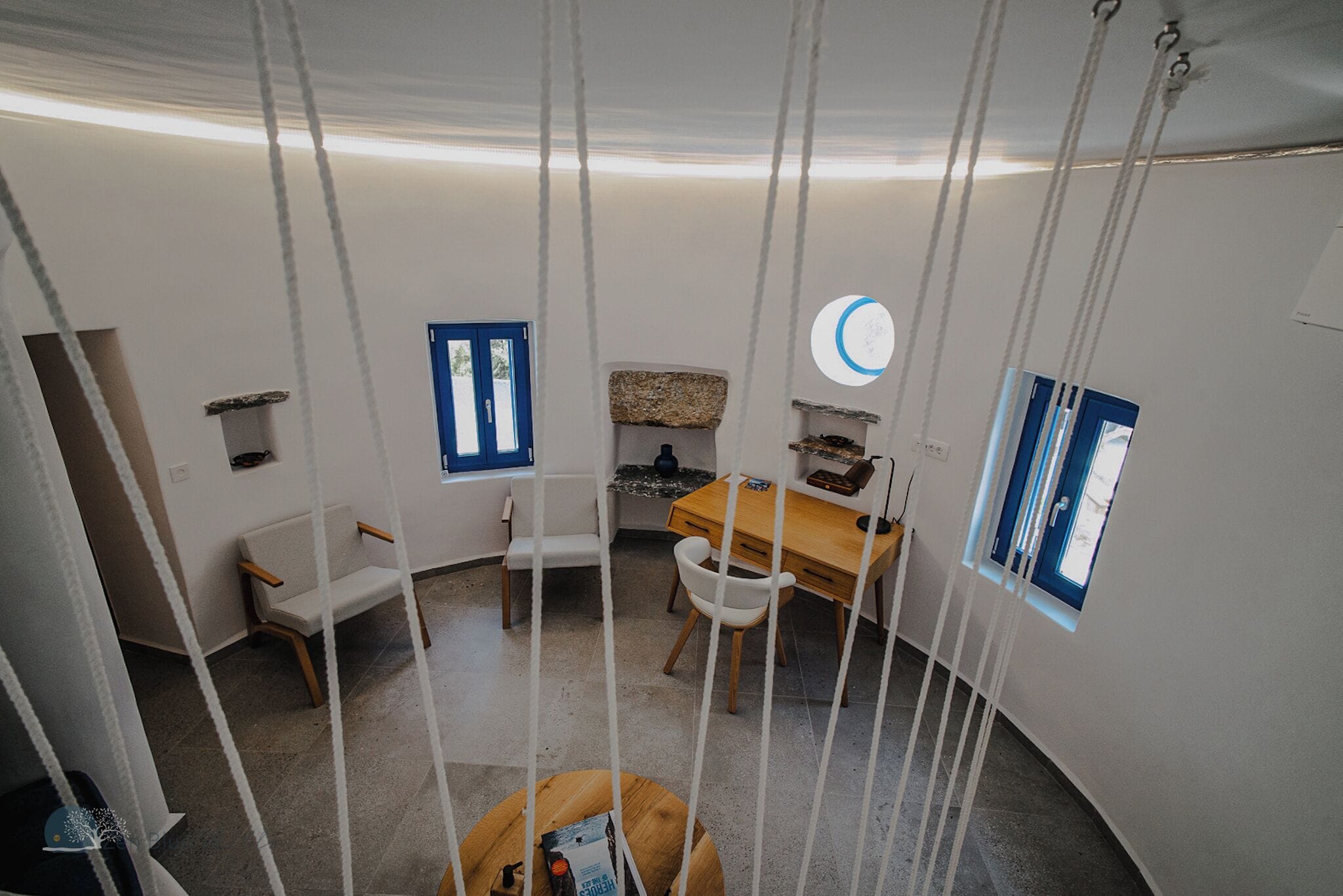 Une pièce comprenant un bureau, des chaises, une petite table et une balançoire suspendue.