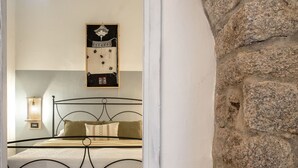 Une chambre à coucher avec un lit, une lampe fixée au mur et une œuvre d’art encadrée au-dessus du lit.