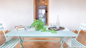 Une table à manger avec des chaises, une plante en pot et une bouteille posée sur un plateau.