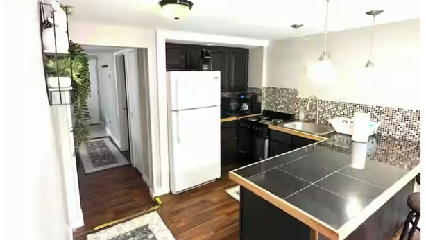 Una cocina moderna con una isla central, piso de madera oscura y alfombra estampada.