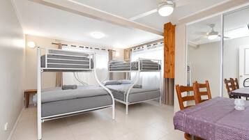 A room with bunk beds, a dining table with chairs, and a ceiling fan.